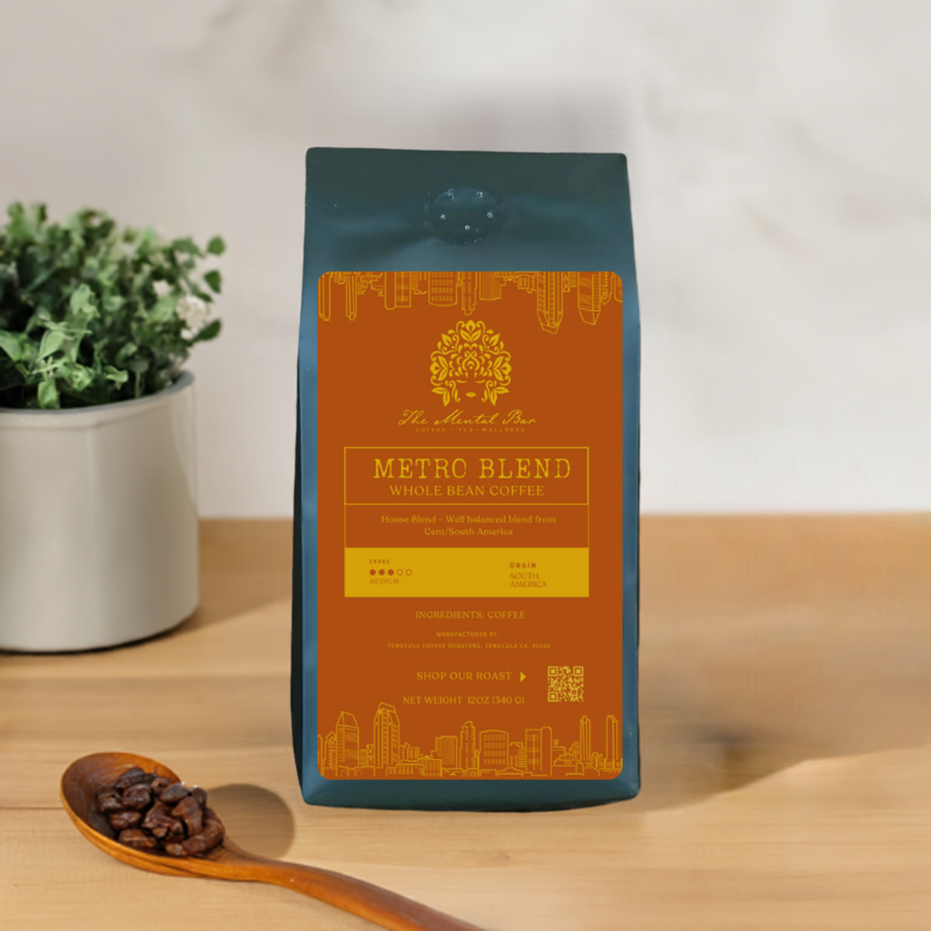 A bag of Metro Blend coffee with a label that showcases the brand, product name, and additional details, placed on a wooden surface next to a plant and a wooden spoon.