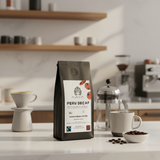 Peru Decaf coffee package on a kitchen counter with coffee-making equipment in the background