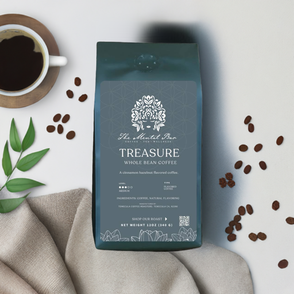 A pack of 'The Mental Bar Treasure Whole Bean Coffee' with a geometric design on the packaging, placed on a linen surface with a cup of coffee and coffee beans scattered around.